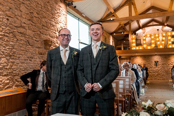 Two smiling groomsmen at wedding venue.