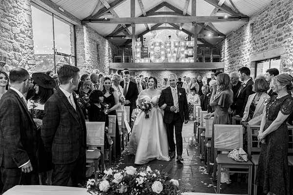 Bride walking aisle with father, wedding ceremony, love sign.