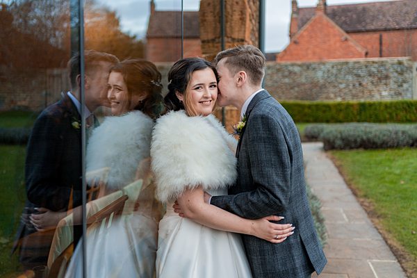 Couple embracing at wedding, reflection in glass.