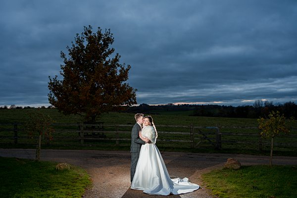 Couple embracing at dusk in countryside wedding.