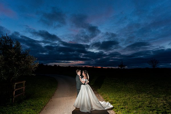 Couple embracing at dusk on country road.