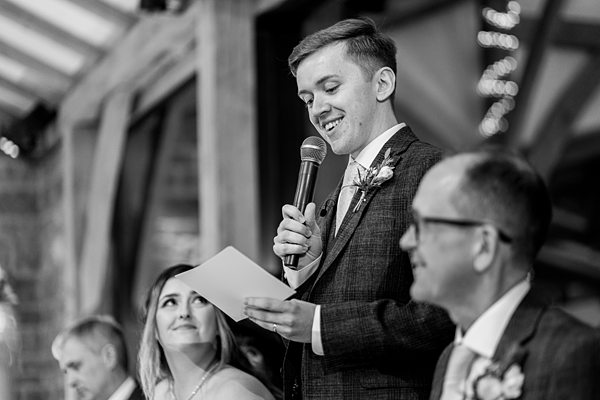 Groom giving speech at wedding reception.