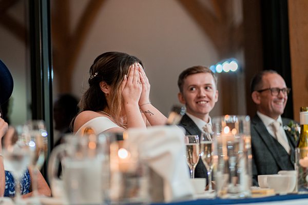 Bride reacting emotionally at wedding reception table.