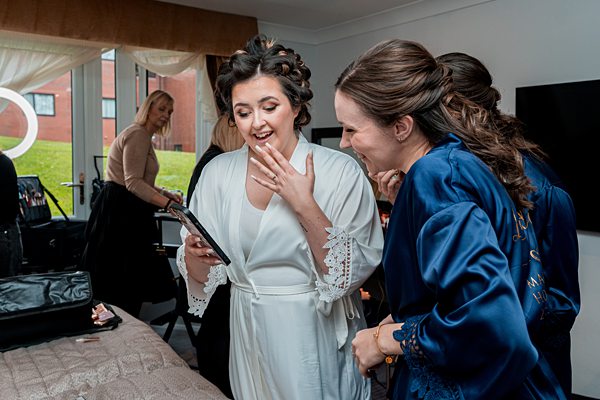 Bride and friend sharing a joyful surprise on phone.
