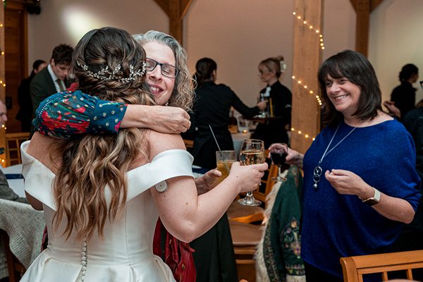 Guests hugging at indoor celebration with drinks.