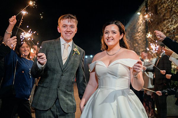 Bride and groom with sparklers at wedding celebration.