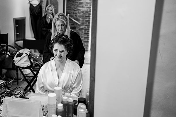 Woman getting hair styled, makeup products on table.