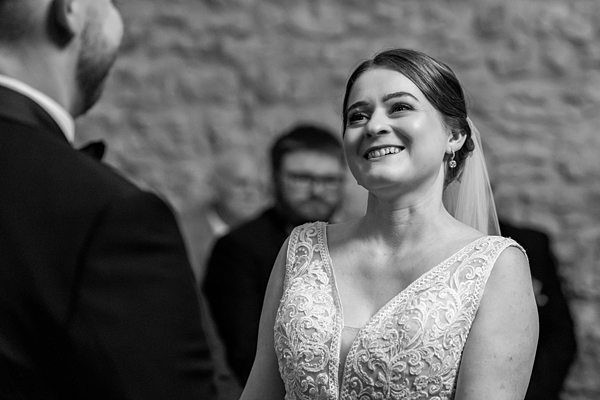 Bride smiling at groom in black and white photo.