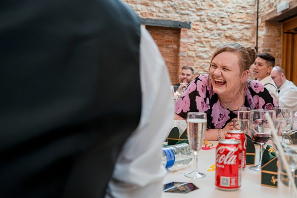 Woman laughing at festive event with drinks.