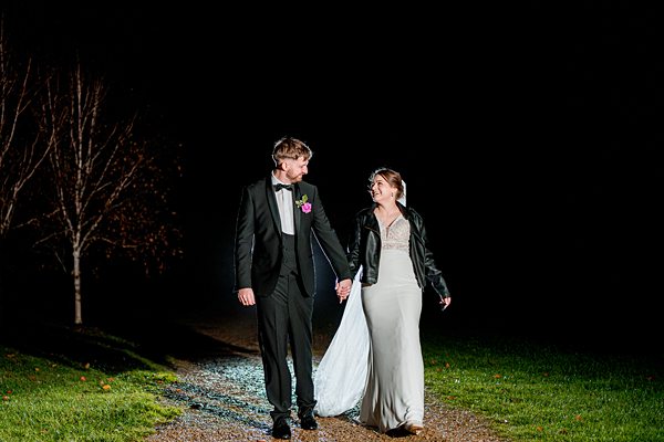 Couple walking at night in wedding attire.