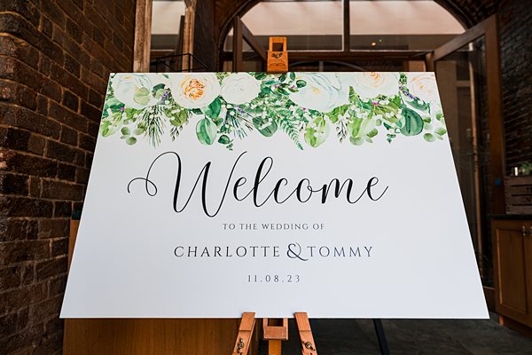 Elegant wedding welcome sign with florals and couple's names.