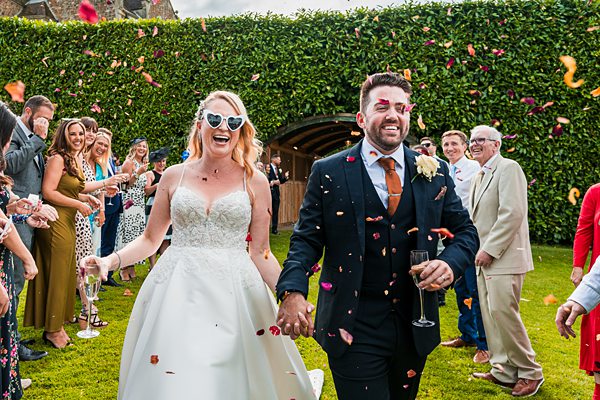 Joyful wedding couple with confetti celebration outdoors.