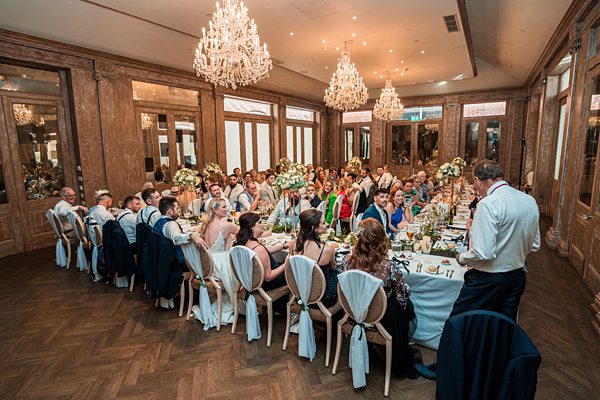 Elegant wedding reception dinner with guests and chandeliers.