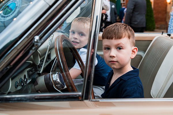 Two boys exploring a vintage car.
