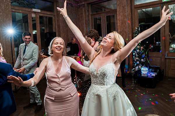 Bride and guests dancing joyfully at wedding reception.