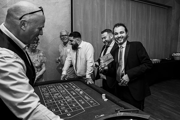 Men enjoying roulette game at casino event in black and white.
