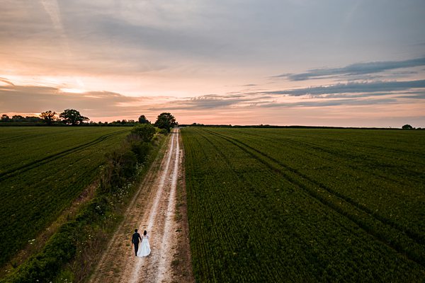 Couple walking down rural path at sunset.