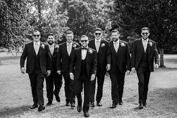 Groomsmen walking, black suits, black and white photo.