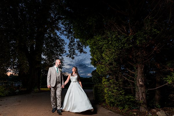 Couple in wedding attire outdoors at dusk