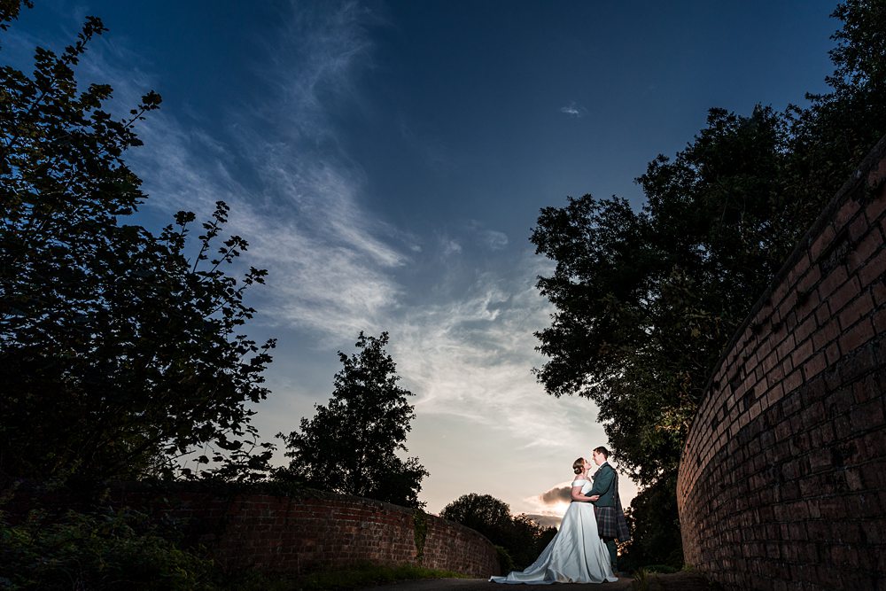 Couple in wedding attire at dusk with dramatic sky