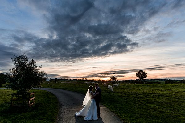 Couple embracing at sunset in countryside setting.