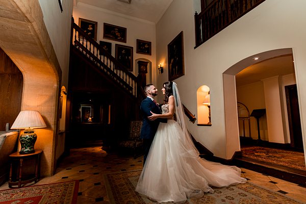Couple embracing at elegant staircase wedding venue.
