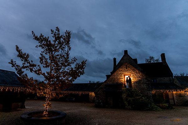 Twilight over quaint stone cottage with festive lights.