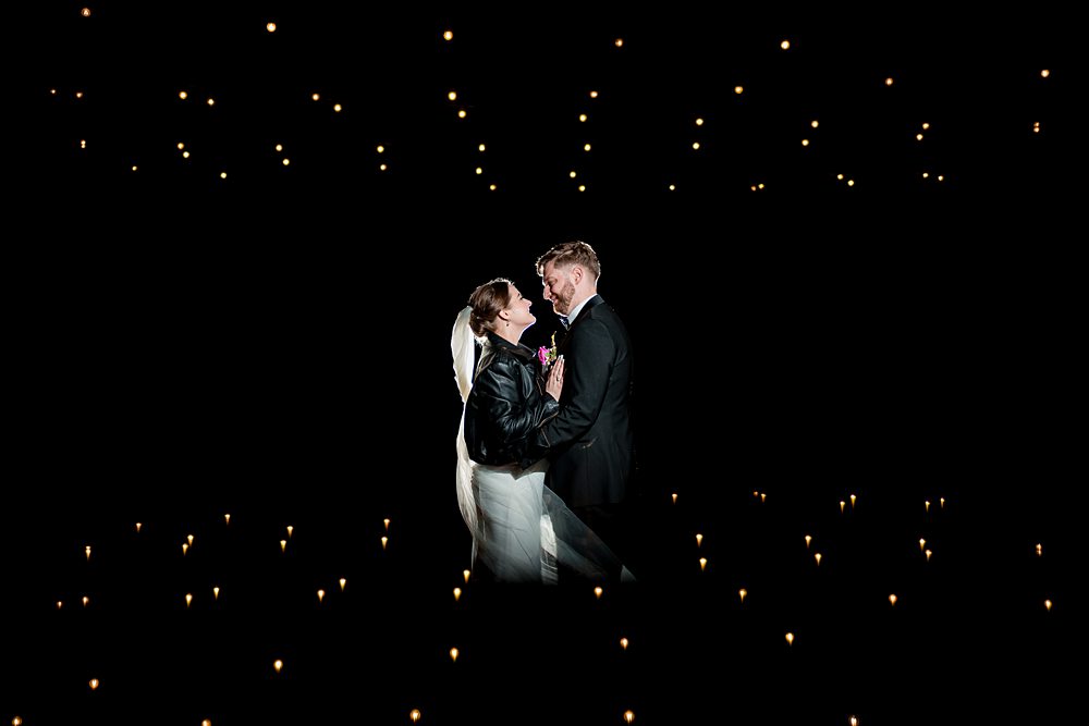 Couple embracing at night with twinkling lights.