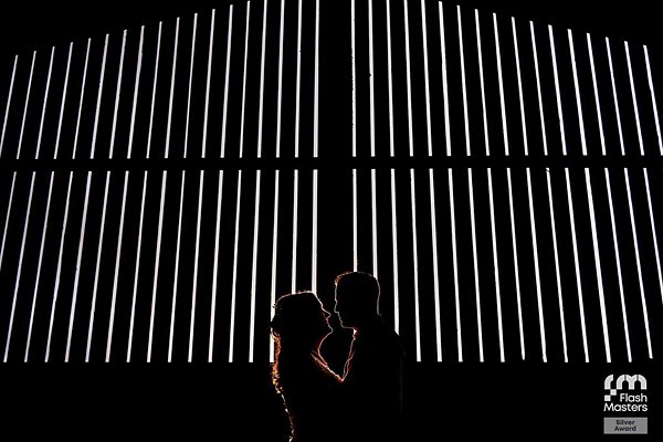 Silhouetted couple against illuminated vertical lines.