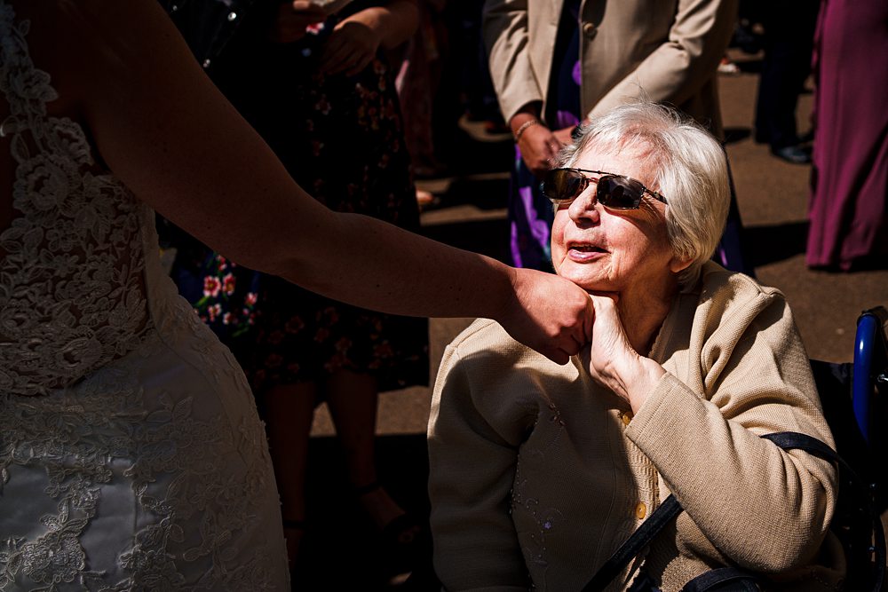 Elderly lady and bride holding hands at wedding.