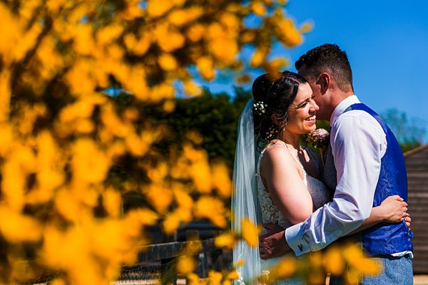 Bride and groom embracing on sunny day.