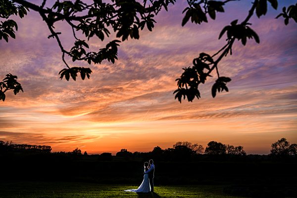Couple embracing at sunset in countryside.