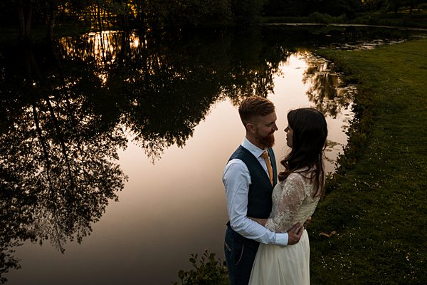 Couple embracing by lake at sunset.