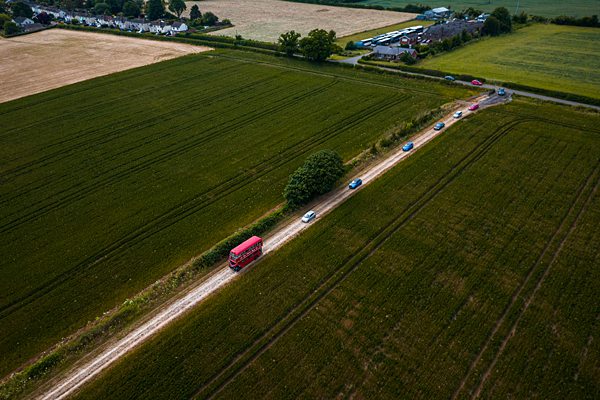 Aerial view of vehicles on rural road amidst fields.