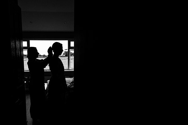 Silhouette of two people by window.