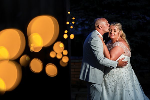 Couple embracing at twilight, wedding, bokeh lights.