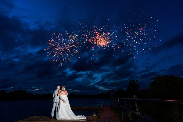 Couple kissing under night sky fireworks display.