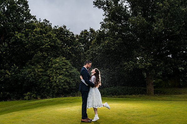 Couple embracing in park with dramatic sky.