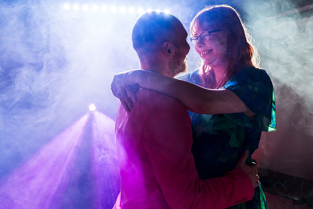 Couple dancing in colourful smoke-filled room.