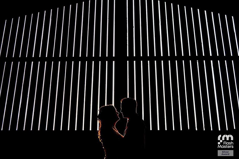 Silhouetted couple against illuminated vertical lines