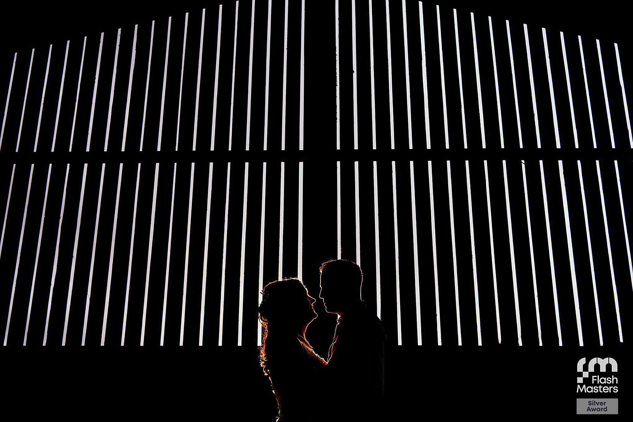 Silhouette of couple against illuminated vertical stripes.