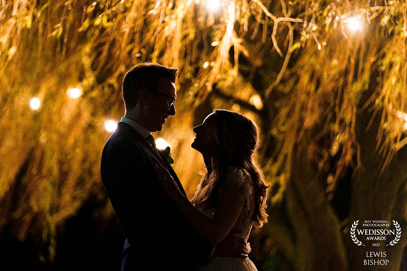 Couple embracing under twinkling lights at night.
