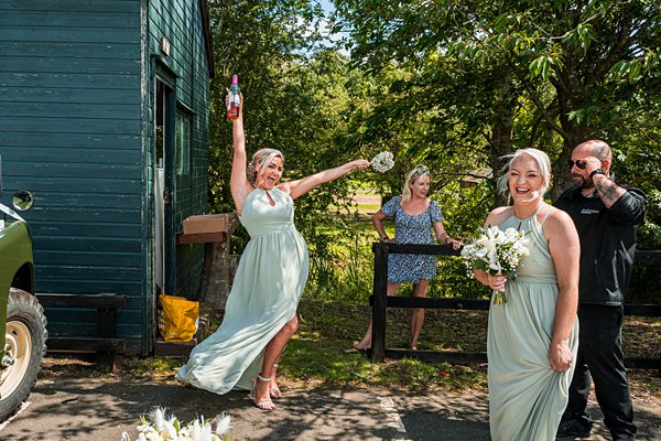 Bridesmaids celebrating outdoors with flowers and champagne.