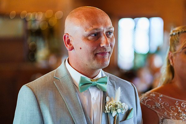 Groom in suit with bow tie at wedding ceremony.