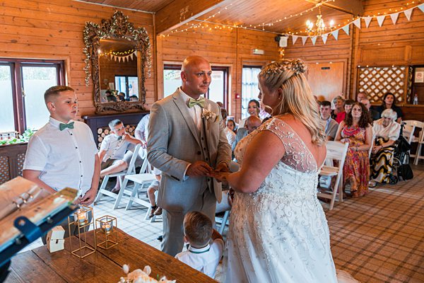 Wedding ceremony inside rustic venue with guests watching.