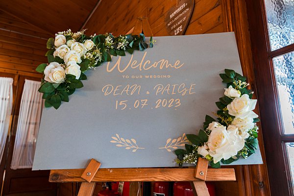 Elegant wedding welcome sign with date and floral decoration.
