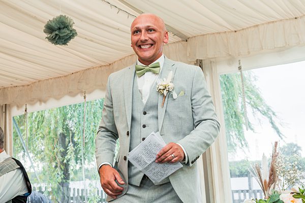 Groom smiling in suit at wedding reception.