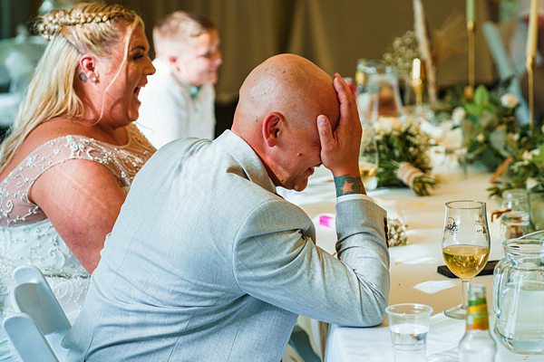Wedding guests reacting at reception table.