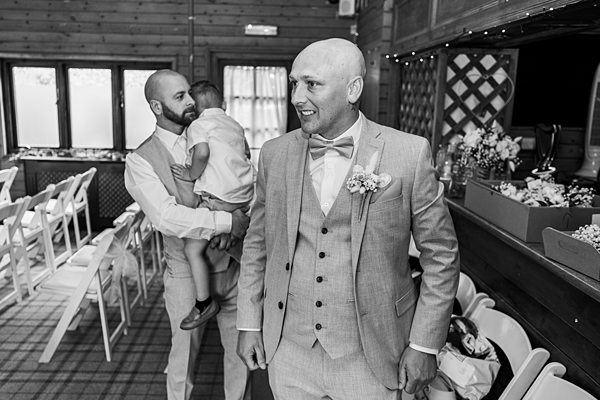Groom waiting with child at wedding ceremony in grayscale