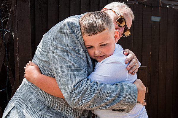 Child embracing grandfather with glasses outdoors.